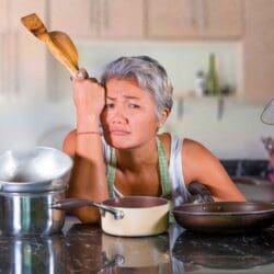 A woman on vacation stressed out and overwhelmed at having to prepare food on vacation.