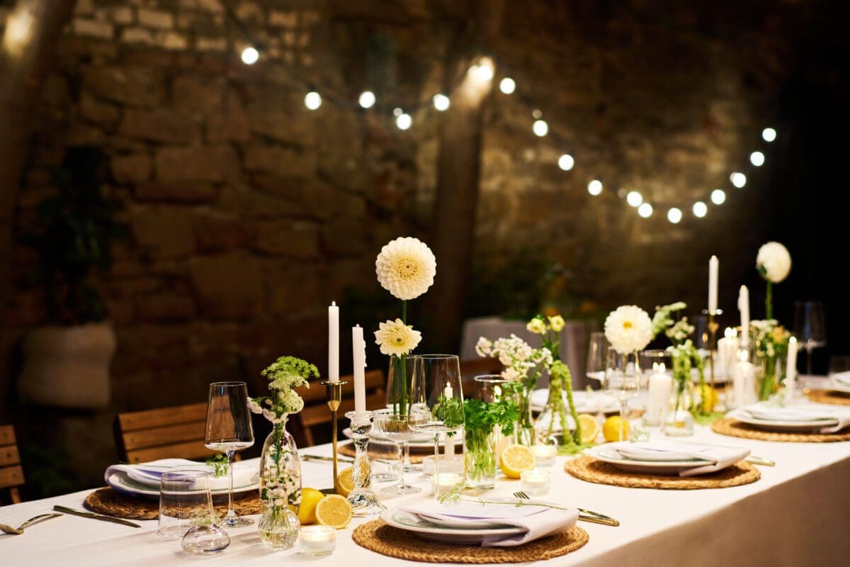 Served dinner table with plates, napkins, wineglasses, flowers and candles prepared for a Private Maui Chef dinner.