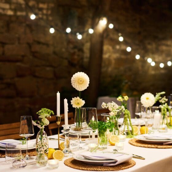 Served dinner table with plates, napkins, wineglasses, flowers and candles prepared for a Private Maui Chef dinner.
