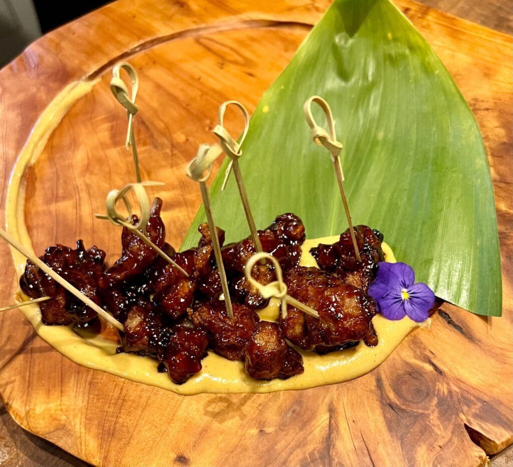 Mochiko Chicken appetizer on a wooden serving tray with sauce. Experience the best private chef on maui.